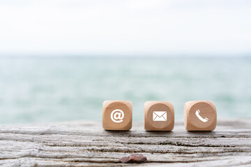 contact us icon (phone, email, mail ) on wood cube, customer service and support. beach and sea...