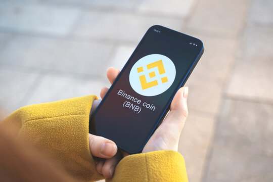 Binance coin BNB cryptocurrency symbol, logo. Business and financial concept. Hand with smartphone, screen with crypto icon close-up
