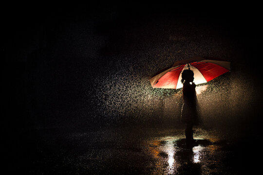 Silhouette of girl under umbrella in the rain