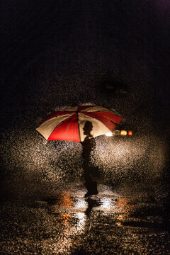 Laughing girl under umbrella lit by headlights