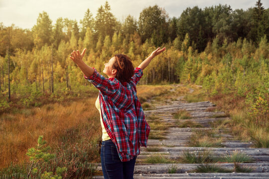 Happy girl with arms outstretched looks towards the sun