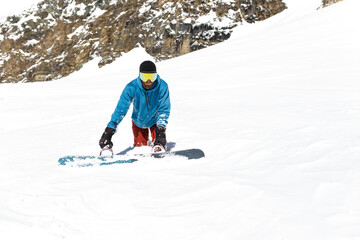 Full length image of a snowboarding standing in a snow, walks hard, stuck in the snow, isolated mountain background.