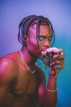 Eccentric shirtless black man kissing flowers.