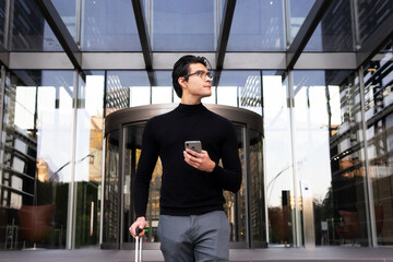 Asian businessman with suitcase browsing smartphone
