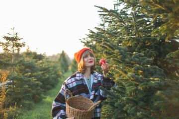 Christmas. Happy young woman in red hat and sweater decorates the Christmas tree. Christmas tree market.