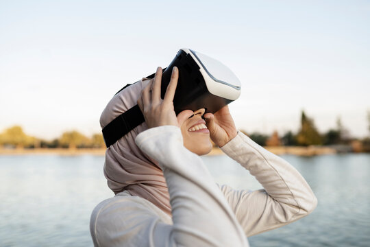 Arab woman in VR headset on embankment