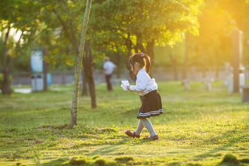 A girl playing with a paper airplane in the park