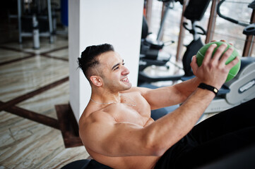 Fototapeta na wymiar Muscular arab man training in modern gym. Fitness arabian men with naked torso doing exercises with ball.