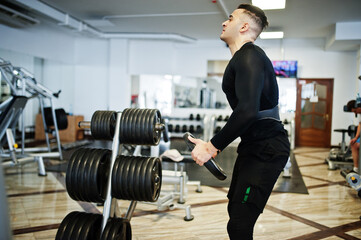 Muscular arab man training with dumbbells in modern gym.
