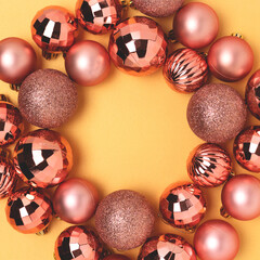 Round frame made of rose gold colored Christmas baubles. Festive concept with copy space.