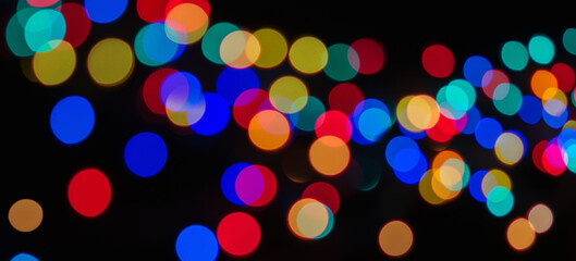 Circles of irregular shapes of different colors on a black background. Abstract lights.