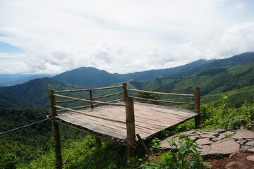 Fototapeta premium Bamboo terrace at the viewpoint on the top of the hill with beautiful landscape of mountains and clouds in Doi Phu Kha National Park, Nan Province, Northern Thailand.