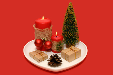 White plate with a red candle and dried oranges and a pine cone. Mini tree.