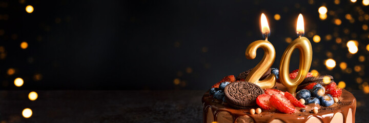 Banner with Chocolate birthday cake with berries, cookies and number twenty golden candles on black...