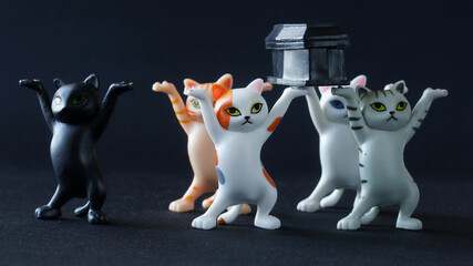 Five cute toy kittens carry a black coffin on a dark background. Concept of a funeral procession dancing with coffin. Stay at home or dance with us. Call for self-isolation from pandemic - obrazy, fototapety, plakaty