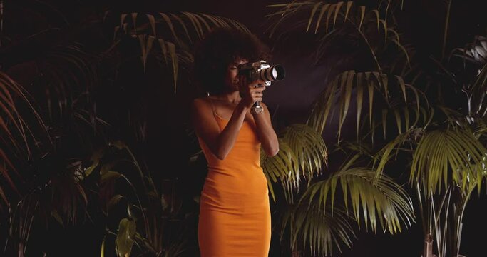 Woman With Afro Hair In Orange Dress With Vintage 8Mm Camera