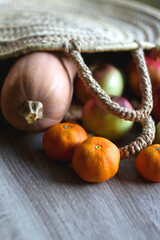 Straw tote bag filled with butternut squash and various fruit. Selective focus.