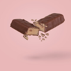 Cracked chocolate bar with milk filling floating in the air isolated on pastel pink background.