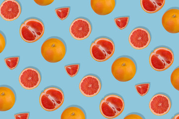Creative pattern with fresh whole and sliced grapefruit on blue background. Minimal fruit concept.