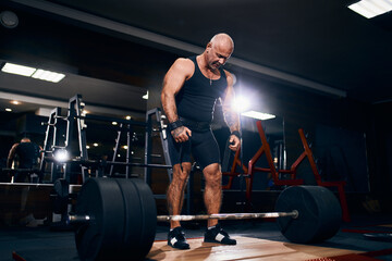 Fototapeta na wymiar Adult bald powerlifter bodybuilder preparing deadlift barbell in gym. Powerlifting. Bodybuilding