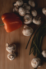 Orange Bell Pepper, Chives and Mushrooms on a Wooden Cutting Board in a Kitchen 