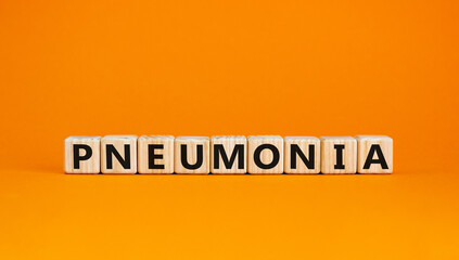 Pneumonia symbol. The concept word Pneumonia on wooden cubes. Beautiful orange table, orange background. Medical and pneumonia concept. Copy space.