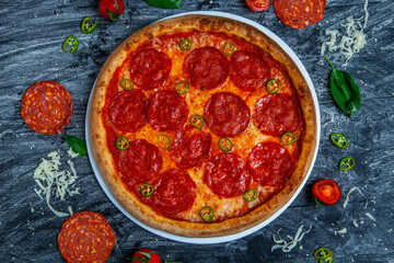 Spicy pizza diavolo on dark wooden background.