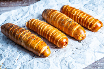 Fresh tasty sausage rolls on plate. fresh sausage in dough on wood background.