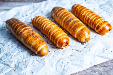 Fresh tasty sausage rolls on plate. fresh sausage in dough on wood background.