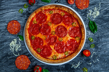 Spicy pizza diavolo on dark wooden background.