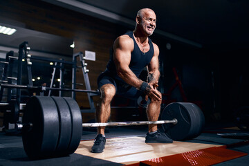 Fototapeta na wymiar Adult bald man powerlifter bodybuilder preparing deadlift barbell in gym. Powerlifting. Bodybuilding