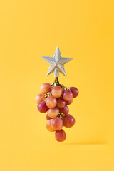 Conceptual idea for celebration tropical New Year with bunch of grapes as Christmas fir tree and...