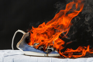 Fototapeta premium Iron on ironing board in flames fire,&nbsp; cause of fire