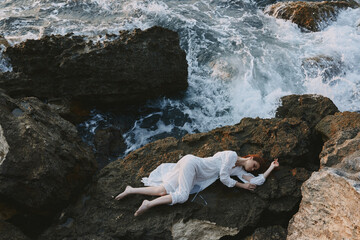 Barefoot woman lying on rocky coast with cracks on rocky surface unaltered