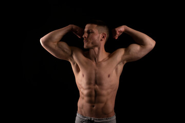 Fototapeta premium Man Showing Biceps Hands Up. Sportsman Showing Muscles. ABS, Biceps Muscles. Black Background. Topless Man Looking to Side