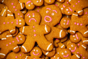 Homemade Christmas gingerbread men full of emotions lie on top of each other close up.