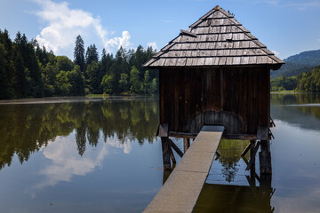 Wooden cabin in the calm water of a pond, Hallegg, Austria