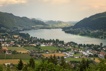 Obraz premium Panoramic view of the town of Pörtschach am Wörther See beside Wörthersee lake on a cloudy day in summer, Austria