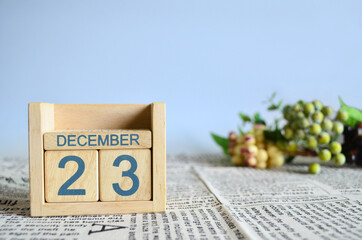 December 23, Calendar cover design with number cube with fruit on newspaper fabric and blue background.	
