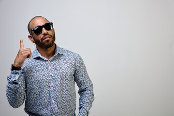 Cool, self-confident Latino man with a beard and a shirt, pointing his finger up, isolated on a white background