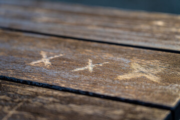 Triple X carved into a brown wooden table in the park