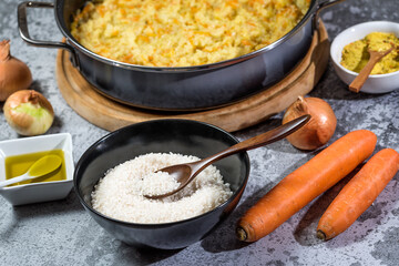 Italian vegan Risotto in a large pan with ingredients - rice, onion, carrots, spices, olive oil