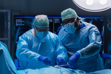 Multiracial team of professional medical surgeons performs the surgical operation in a modern hospital. Doctors are working to save the patient. Medicine, health, cardiology and transplantation.