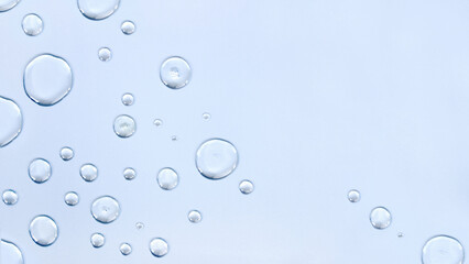 Transparent drops close-up on a light blue background. Top view, place for text