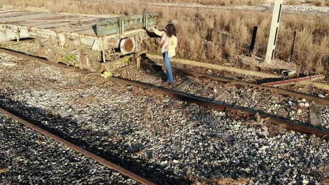 modelo en v&iacute;as del tren junto a parte trasera de un vag&oacute;n posando y mostrando modelo de ropa.