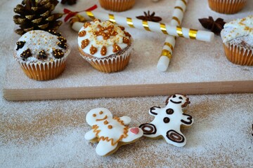 Christmas composition: Christmas cupcakes decorated with icing and surrounded by cinnamon sticks and star anise on a background of powdered sugar