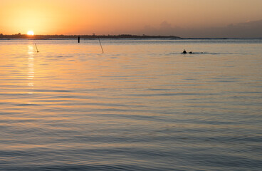 Dramatic image of a sunrise over the Caribbean bay in Boca Chica, Dominican Republic with a lobster fishing in silhouette on the horizon.