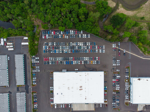 Aerial view. Large paved car parking. Lots of greenery, trees, bushes. Lots of parked cars. Suburb. Infrastructure, planning, travel, tourism, camping, environmental protection.