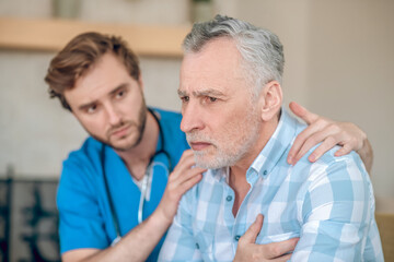 Attentive cardiologist supporting a frightened sick man