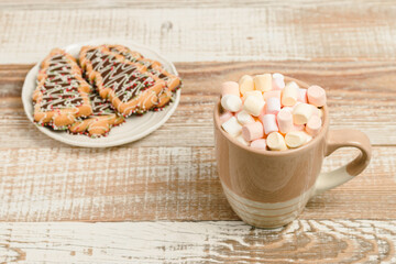 Cup of hot chocolate with marshmallows and Christmas cookies at the background